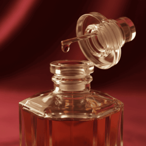 Macro photography of a crystal perfume extract bottle with a precious drop at the end of the stopper, illustrating the highest concentration and richness of raw materials.