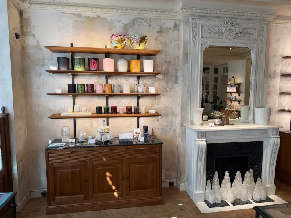 Présentation des célèbres bougies parfumées sur les étagères de la boutique Diptyque.