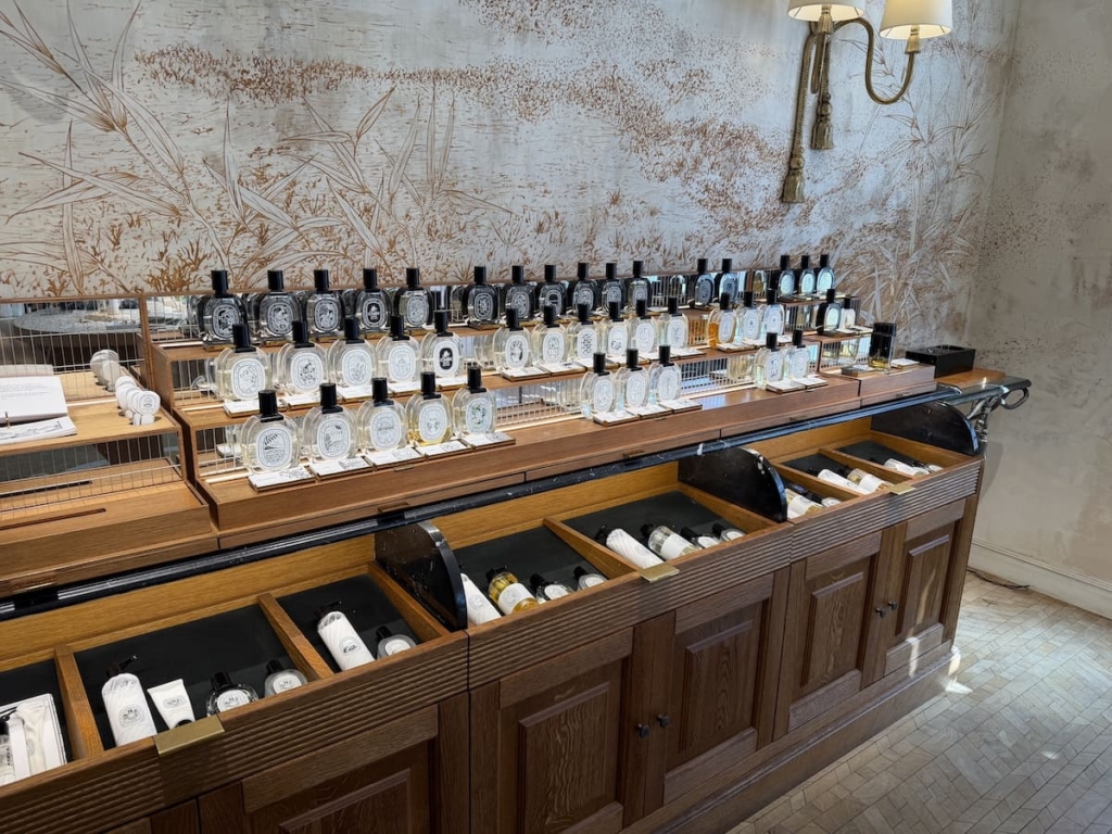 Collection des eaux de parfum Diptyque exposée sur une console en bois en boutique.