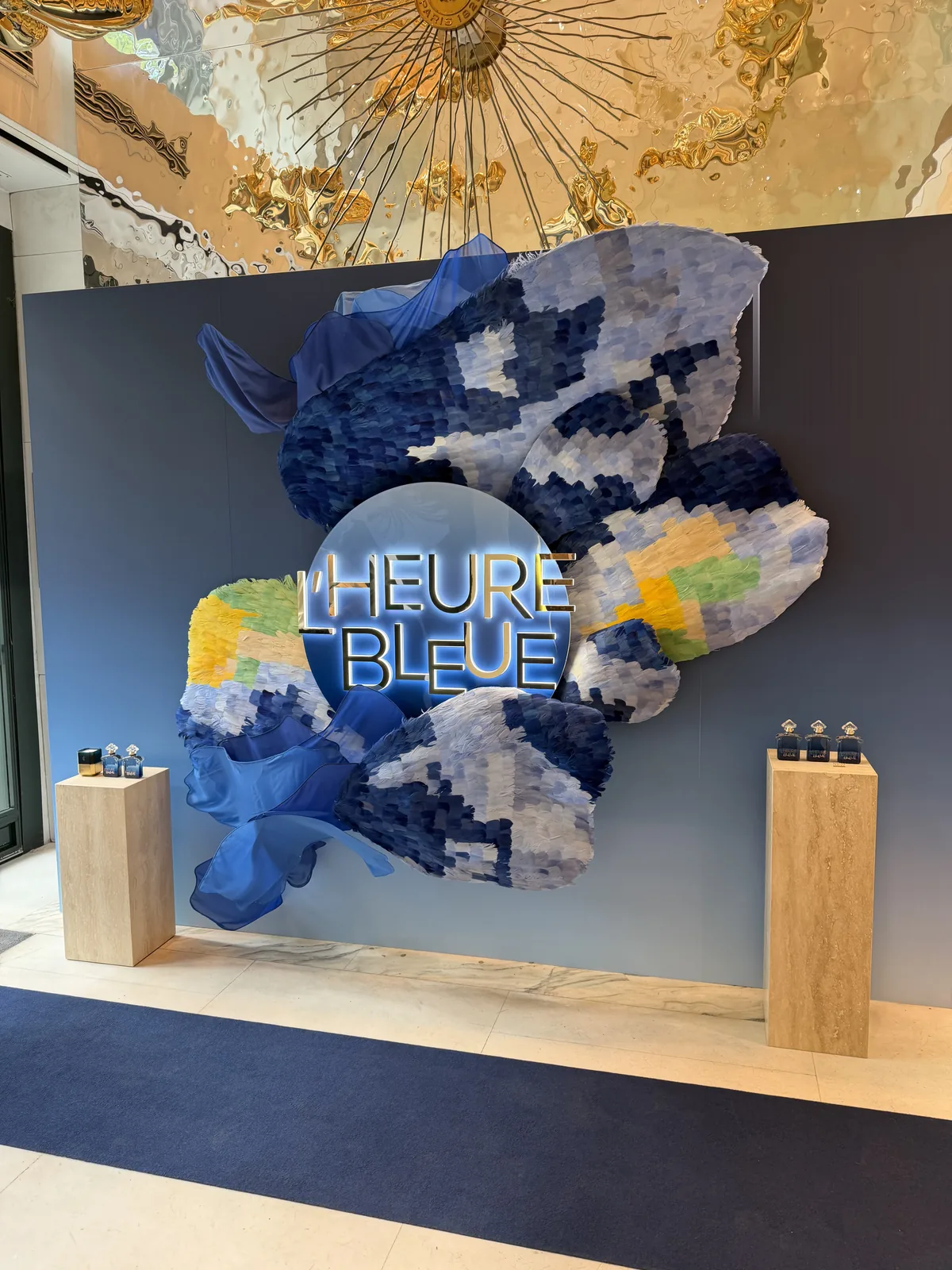 Décor mural L'Heure Bleue aux pétales peints en volume dans la boutique Guerlain.