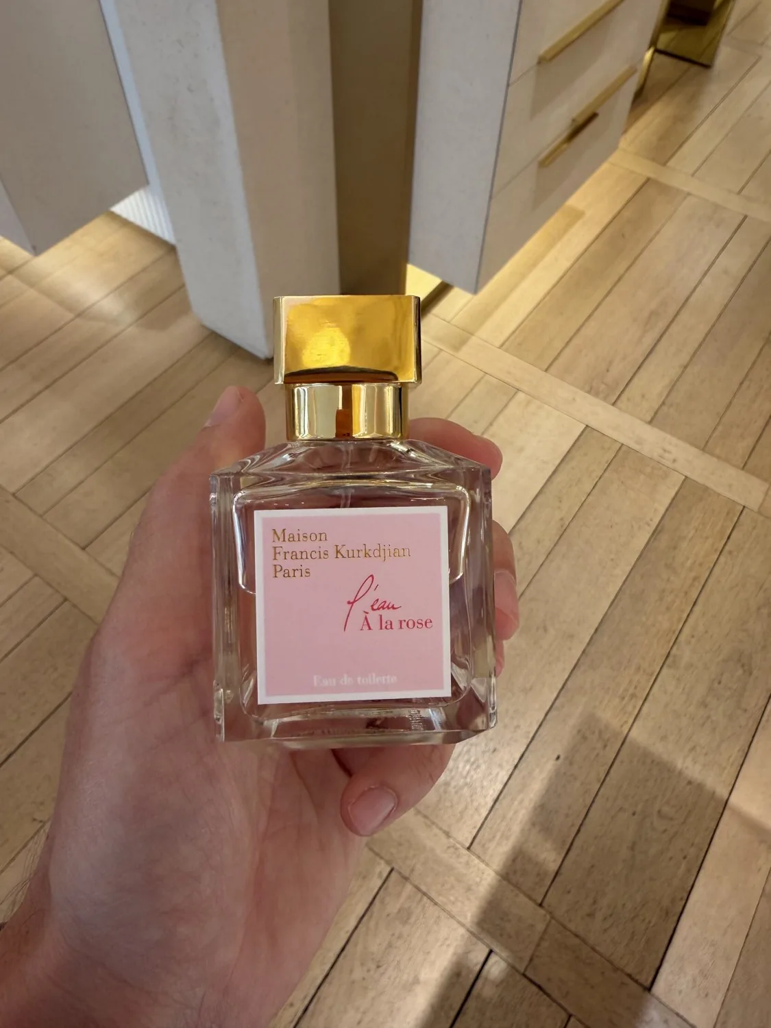 Flacon de L'eau À la rose de Maison Francis Kurkdjian tenu en main en boutique.