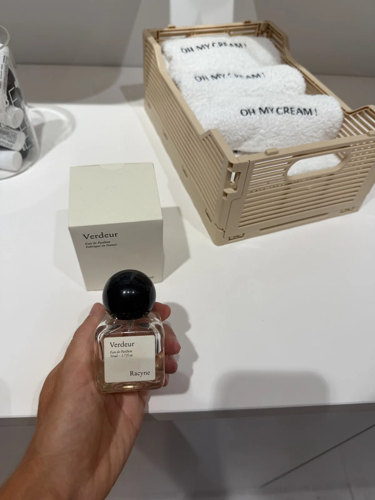Flacon de Verdeur de Racyne tenu en main devant son coffret, en boutique.