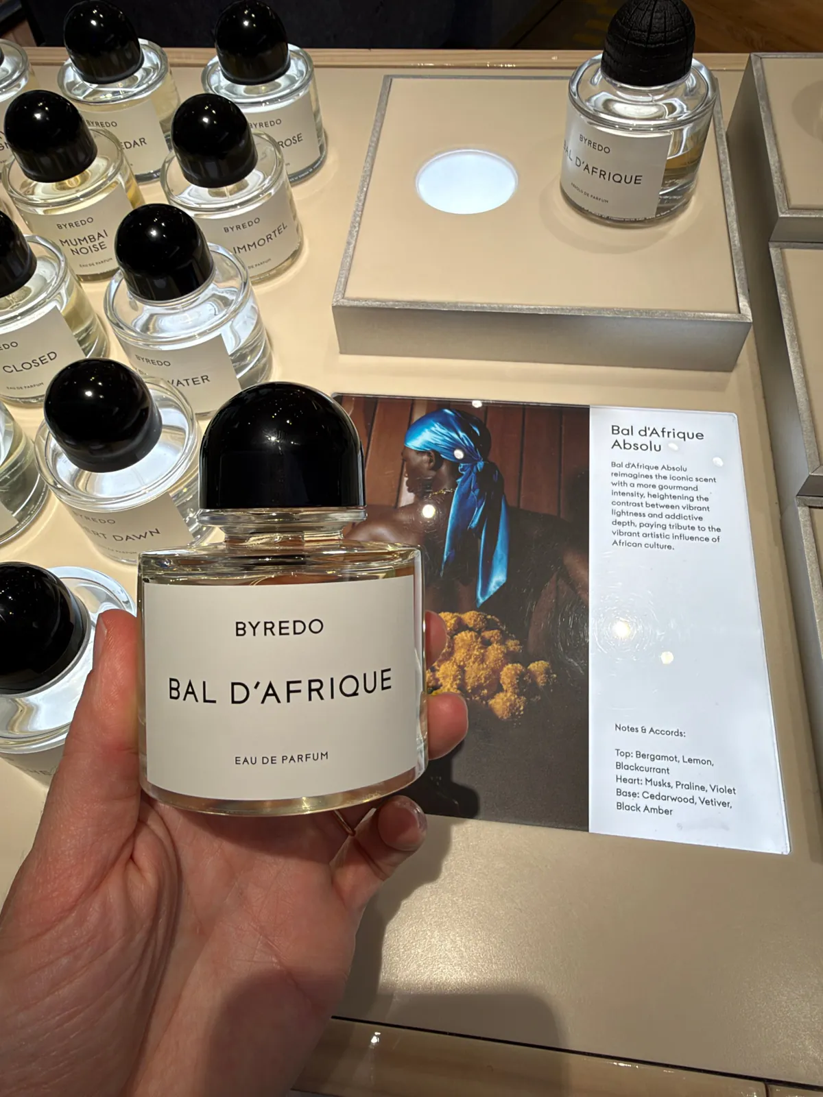 Flacon d'eau de parfum Bal d'Afrique de Byredo tenu en main au corner du Bon Marché.