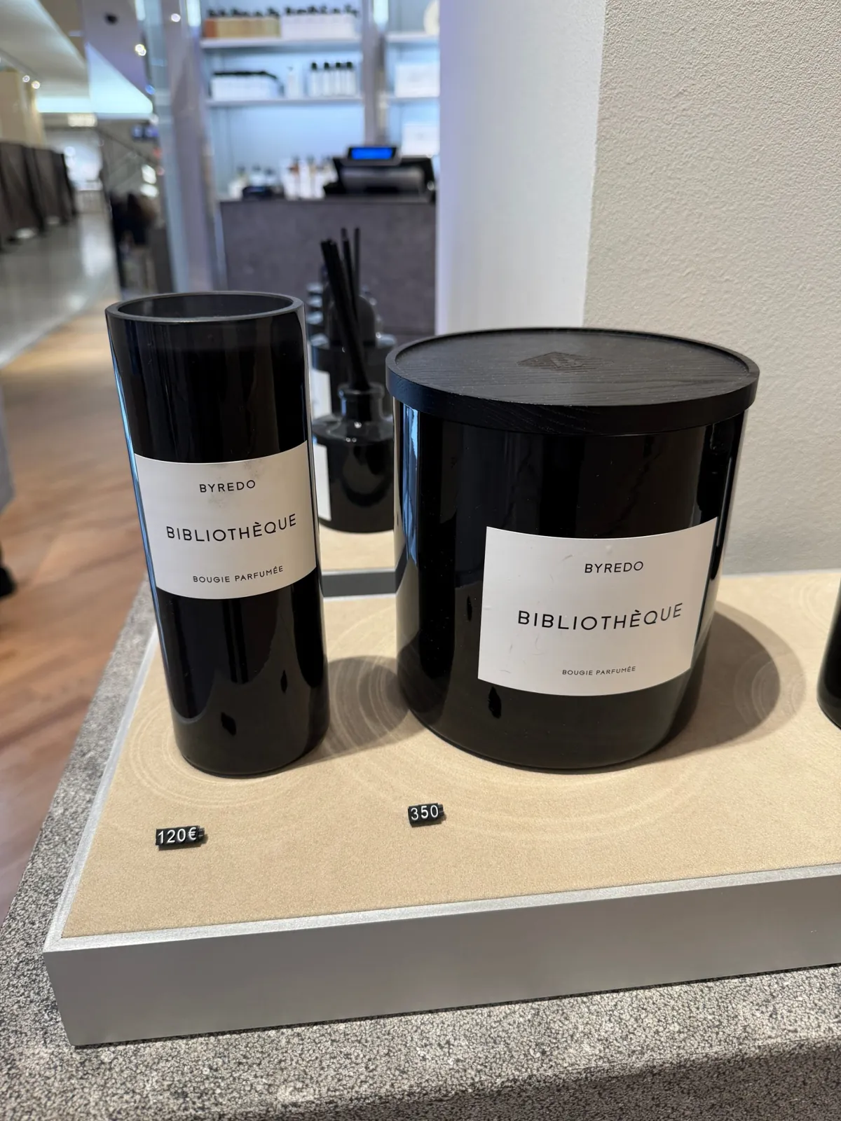 Deux bougies Bibliothèque de Byredo, en format haut et en grand format, au corner du Bon Marché.