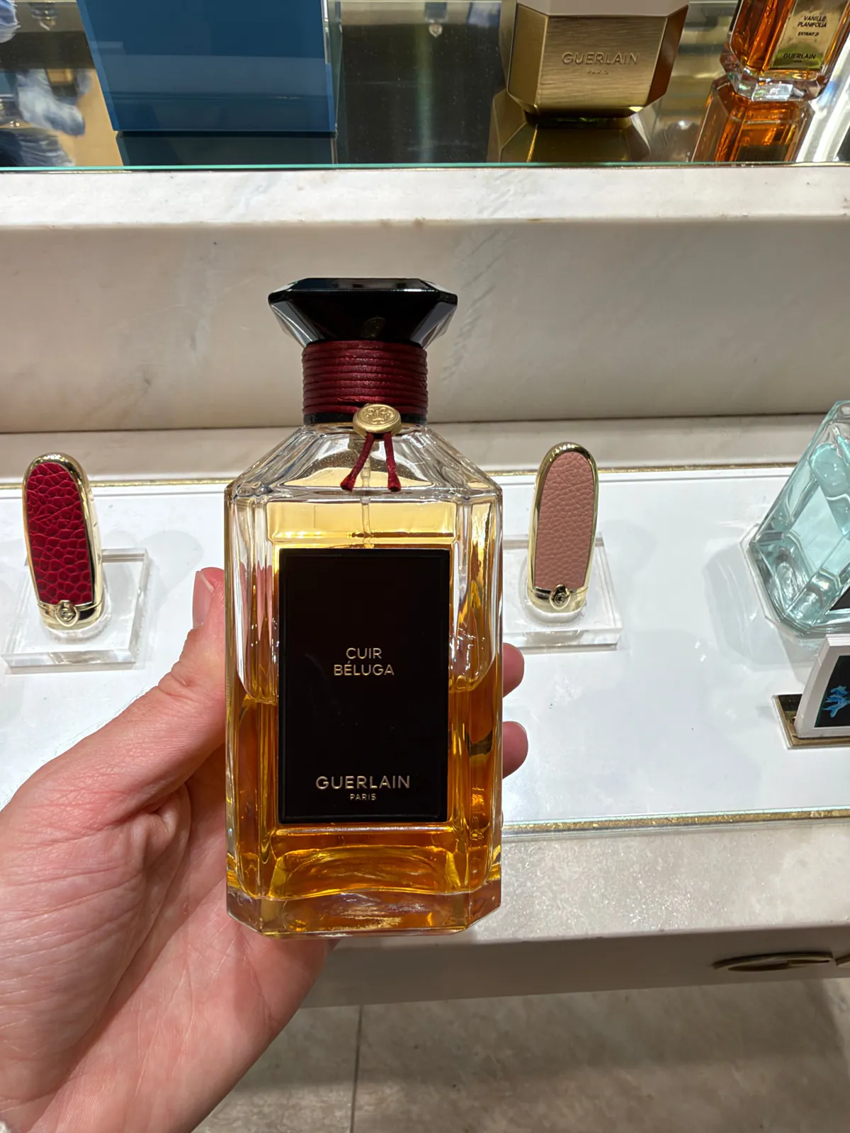Flacon de Cuir Béluga de Guerlain tenu en main au comptoir L'Art et la Matière.