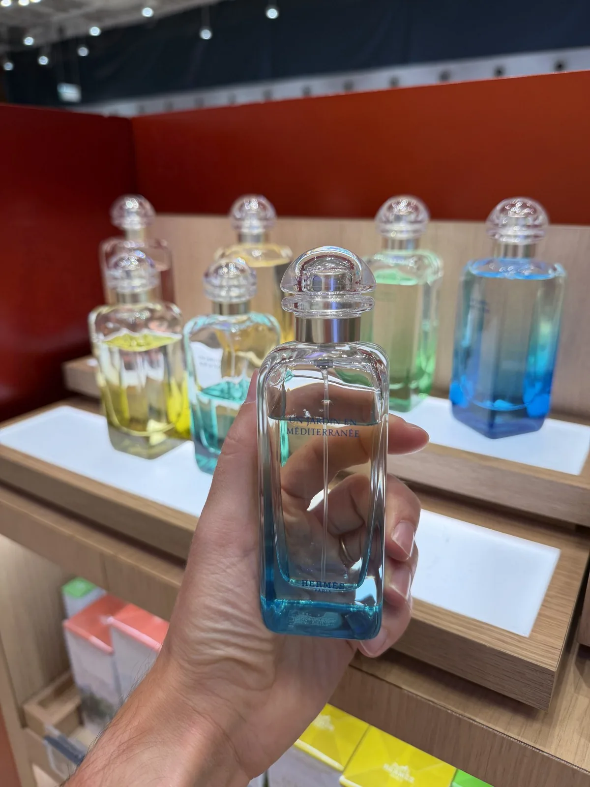 Flakon von Un Jardin en Méditerranée von Hermès in der Hand, vor den anderen Jardins des Hauses.