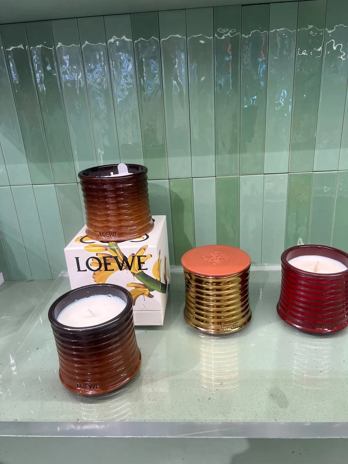 Bougies parfumées Loewe dans leurs contenants en céramique striée, dorée, rouge et brune.